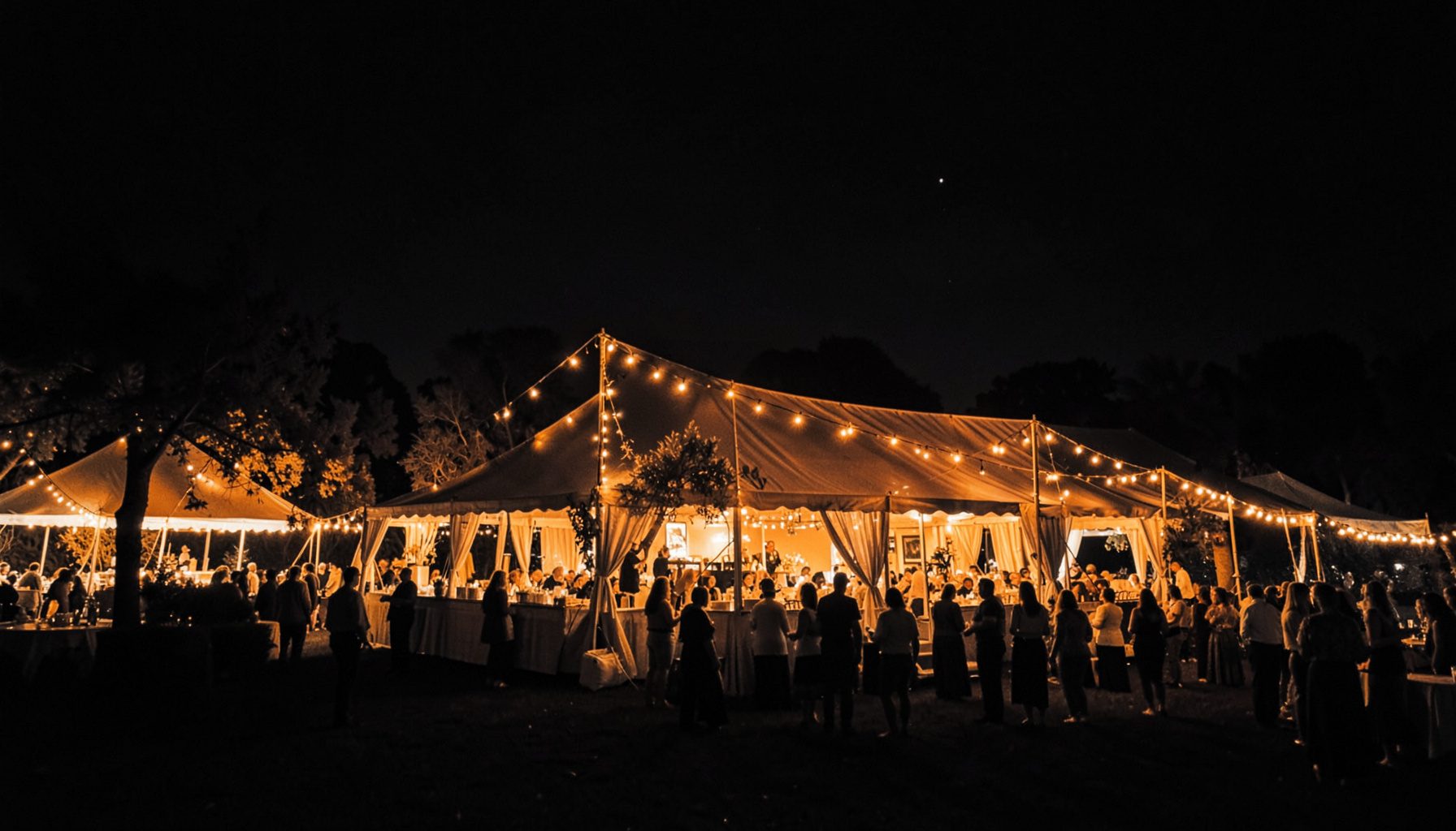 A festival venue exterior at night with warm amber lighting against a dark sky, elegant and celebratory