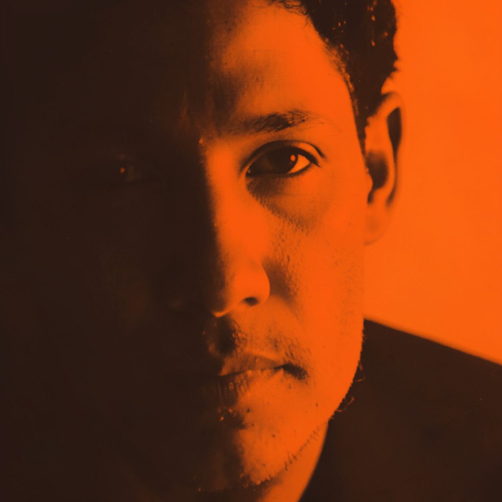 Cropped duotone portrait of two brothers standing close together, rendered in deep navy and warm amber tones