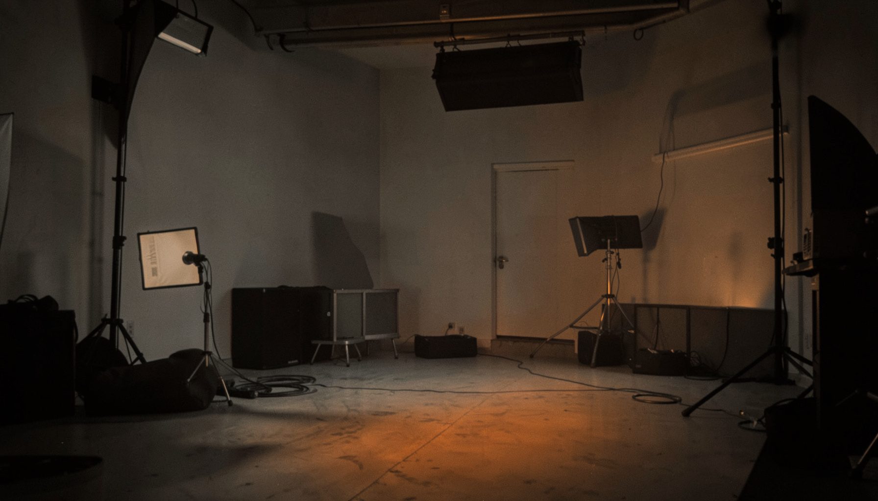 A softly lit film set interior in muted grays and warm amber tones, quiet and contemplative