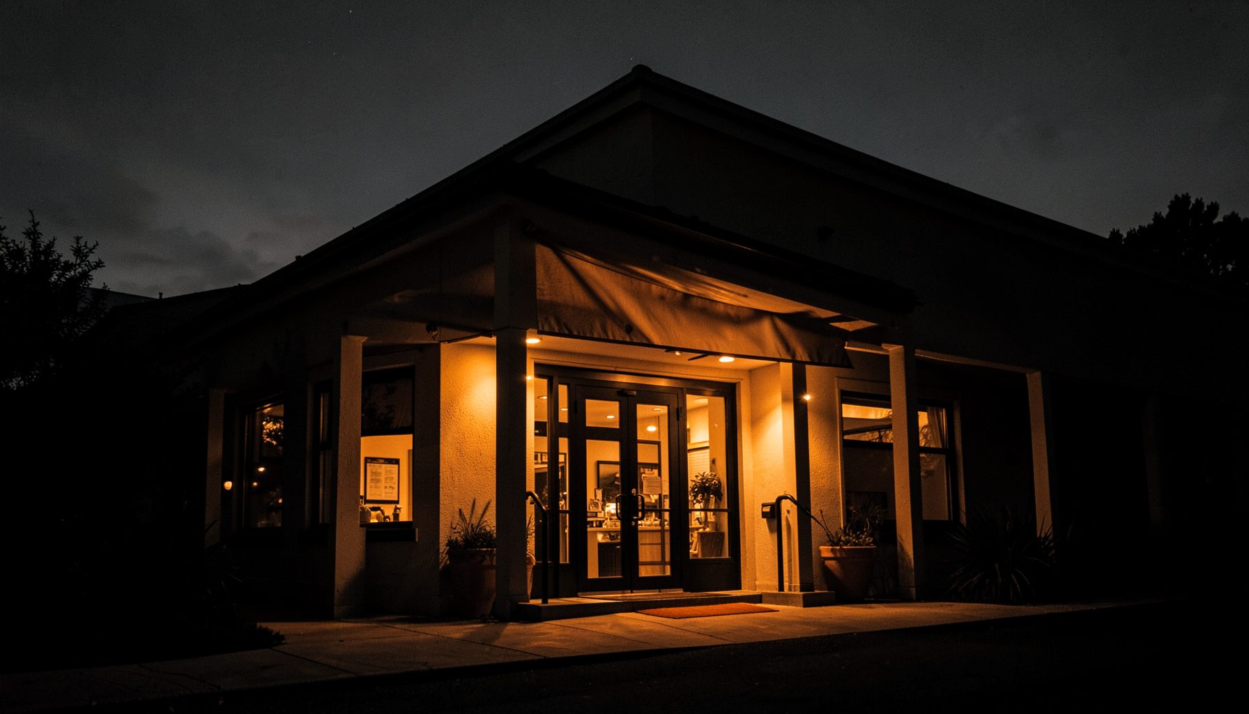 An exterior cinema entrance at dusk, warm amber lights against a darkening sky, elegant and inviting
